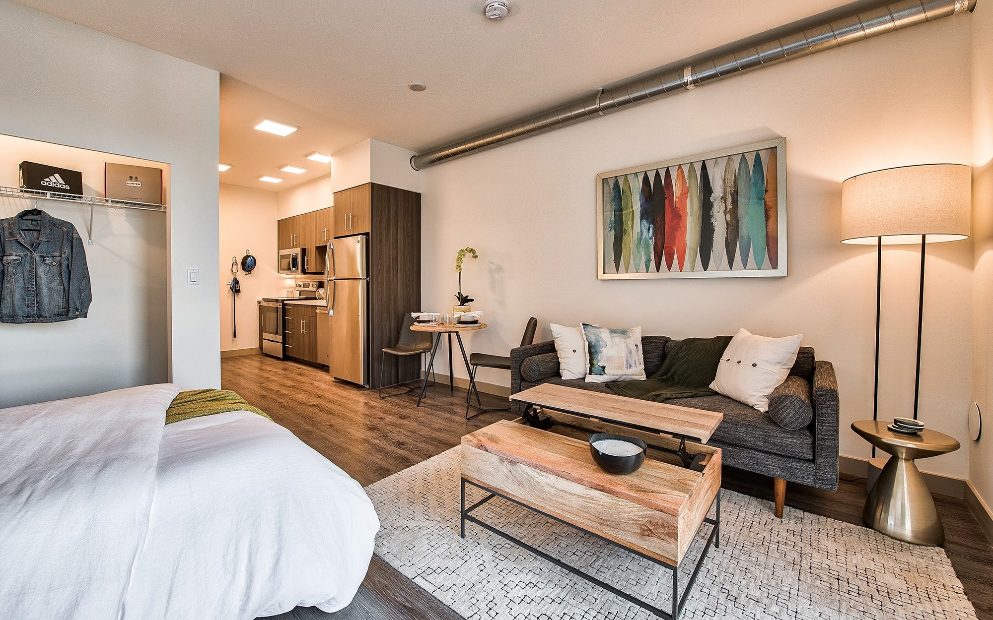 Furnished studio apartment with wood flooring and a one-wall style kitchen